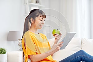 Happy asian woman with tablet pc and apple at home