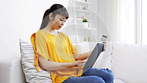 Happy asian woman with tablet pc and credit card