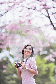 Happy asian woman tourist in spring blossom park walking and take a photo leisure activity