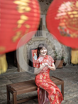 Happy asian woman in traditional chinese dress holding a red pocket with Chinese one hundred Yuan banknotes- lucky money. Tet