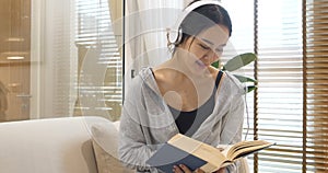 Happy asian woman use headphones listen to music reading book