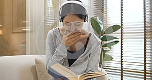 Happy asian woman use headphones listen to music reading book