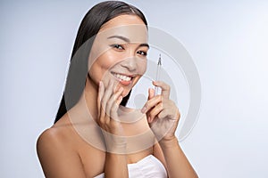 Happy Asian woman is using comedone extractor