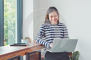 Happy asian woman using on laptop computer and listening music w