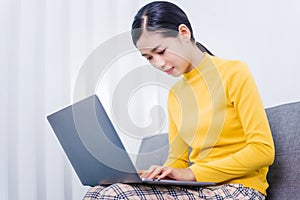 Happy asian woman using laptop while sitting on sofa in living room, WFH work from home concept