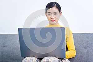 Happy asian woman using laptop while sitting on sofa in living room, WFH work from home concept photo