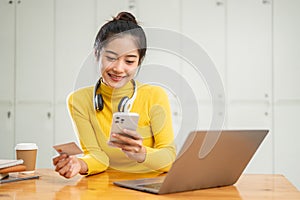 A happy Asian woman using a mobile banking application to transfer her money or pay bills online