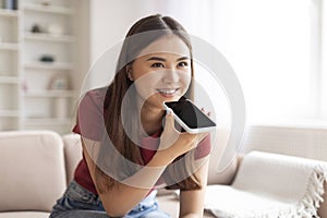 Happy Asian Woman Using Virtual Voice Assistant Option On Smartphone At Home