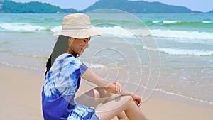 Happy Asian woman wear sunscreen to protect her skin at the beach during travel holidays vacation outdoors at ocean or nature sea