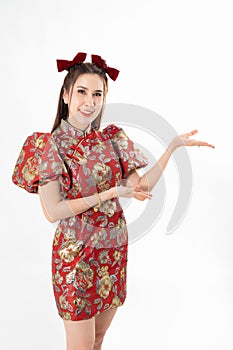 Happy Asian woman wearing traditional cheongsam qipao dress and hand gesture up pointing up to copy space isolated on White