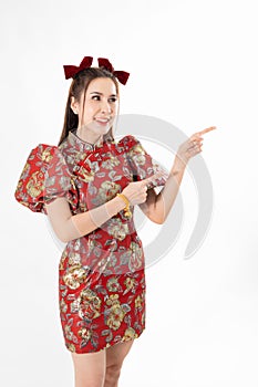 Happy Asian woman wearing traditional cheongsam qipao dress and hand gesture up pointing up to copy space isolated on White