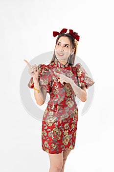 Happy Asian woman wearing traditional cheongsam qipao dress and hand gesture up pointing up to copy space isolated on White