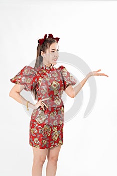 Happy Asian woman wearing traditional cheongsam qipao dress and hand gesture up pointing up to copy space isolated on White