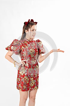 Happy Asian woman wearing traditional cheongsam qipao dress and hand gesture up pointing up to copy space isolated on White