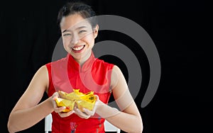 Happy Asian woman wearing traditional red costume, presenting and holding golds, smiling to celebrate Chinese New Year and make