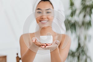 Happy asian woman wrapped in towel representing cream jar