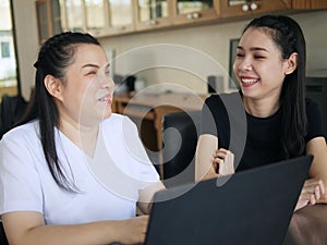 Happy Asian women co-workers in workplace including person with blindness disability using laptop computer with screen reader photo