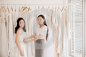 Happy asian women designer making adjustment in fashion studio,Asian bride smling and trying on wedding dress