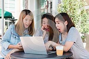 Happy asian women friends giving laptop gift to surprised girl in coffee shop. Shopping online concept.