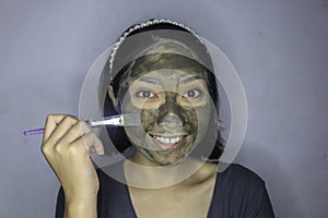 Happy Asian women smiling when she use brush to beauty face mask