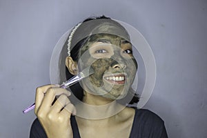 Happy Asian women smiling when she use brush to beauty face mask