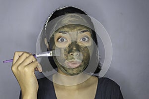 Happy Asian women smiling when she use brush to beauty face mask