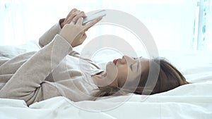 Happy Asian women are using smart phone on the bed in morning.
