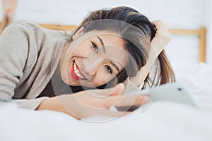 Happy Asian women are using smart phone on the bed in morning.