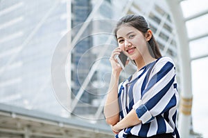 Happy asian young business woman talking on mobile phone in urban city . outdoor