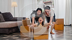 Happy Asian young family having fun laughing moving into new home. Japanese parents mother and father smiling helping excited