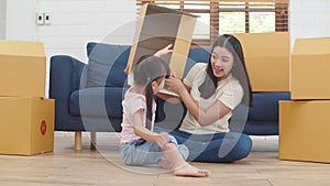 Happy Asian young family homeowners bought new house. Korean Mom and daughter playing together during unpacking in new home after