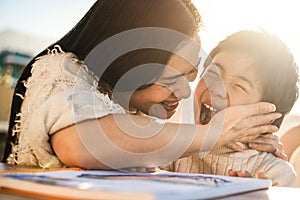 Happy asian young mother having fun with her child outdoors in summer sunny day - Focus on woman face