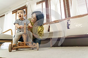 Happy Asian Young Mother playing with her little son at home, Little toddler boy having fun ride on rocking horse