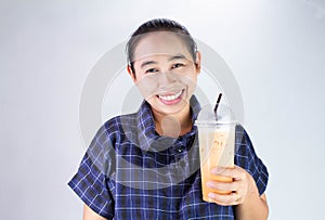 Happy Asian young woman is drinking Thai tea with milk. Popular beverage in Asia