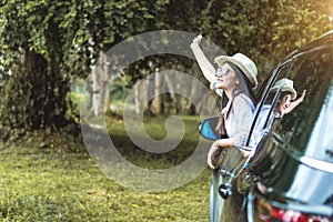 Happy Asian young woman enjoying a ride in a car with hand greeting