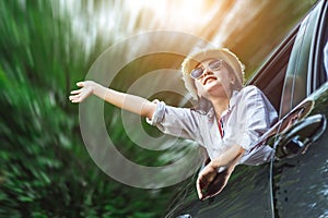 Happy Asian young woman enjoying a ride in a car with hand greeting