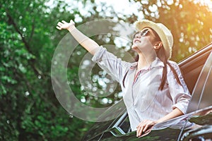 Happy Asian young woman enjoying a ride in a car with hand greeting.