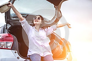 Happy Asian young woman enjoying a ride in a car with hand greeting.