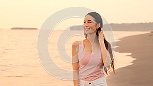 Happy asian young woman walking on the beach at sunset
