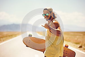 Happy athletic man walks skateboard longboard straight road photo