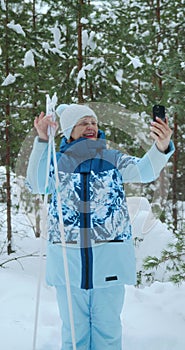 A happy athletic retired woman in a ski suit communicates via video call