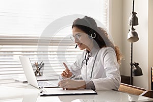 Happy attentive general practitioner in headset using laptop