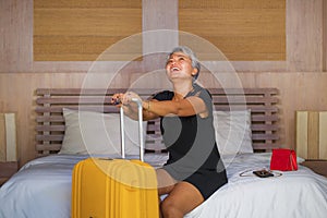 Happy and attractive 40s to 50s mature Asian woman with grey hair arriving in hotel room excited on bed joyful enjoying holiday