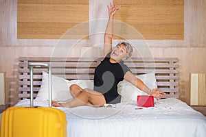 Happy and attractive 40s to 50s mature Asian woman with grey hair arriving in hotel room excited on bed joyful enjoying holiday