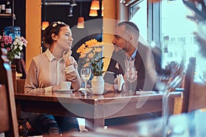 Happy attractive African-American couple in love having a great time together in a restaurant at their dating. A