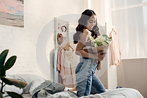 Happy attractive asian girl kneeling on bed and photo