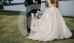 Happy and attractive bride and groom run along the beach holding hands photo