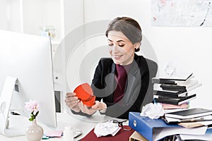Happy attractive businesswoman opening heart shaped red present box