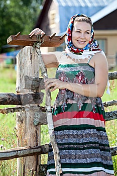Happy attractive country girl in sundress and headscarf against house