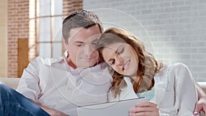 Happy attractive couple viewing photos on tablet, remembering pleasant moments